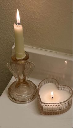 a lit candle sitting on top of a bath tub next to a glass bowl filled with water