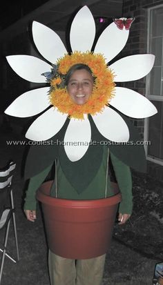 a woman wearing a flower headpiece standing in front of a house with a potted plant