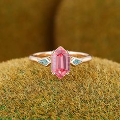 a pink tourmaline ring sitting on top of grass