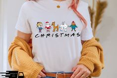 a woman wearing a t - shirt that says christmas with cartoon characters on the front