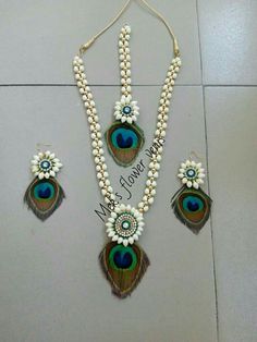 a peacock necklace and earrings with pearls on the bottom, along with other jewelry pieces