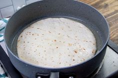 a tortilla being cooked in a skillet on top of a stovetop