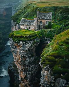 a house on top of a cliff in the middle of a river with moss growing on it