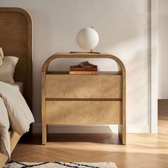 a bed room with a neatly made bed and a night stand on top of it