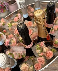 several bottles of champagne and roses on a tray