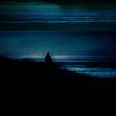 a blurry image of a person standing in front of the ocean at night time