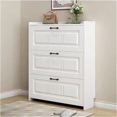 a white chest of drawers in a room with a rug and flowers on the floor