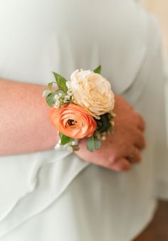 the bride's bouquet is made up of peach and white flowers on her arm