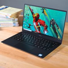 an open laptop computer sitting on top of a wooden table next to stacks of books