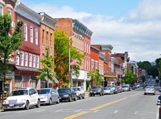 cars are parked on the side of the road in front of buildings and trees,