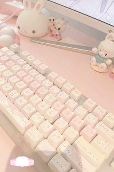 a white keyboard sitting on top of a desk next to a mouse and stuffed animals