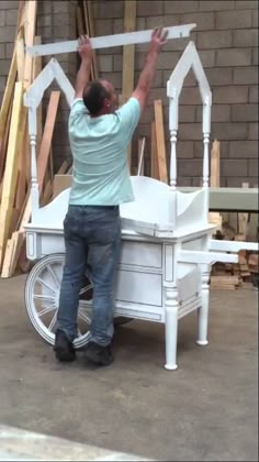 a man standing on top of a white cart next to a building under construction with his hands in the air