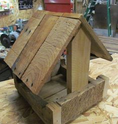 a birdhouse made out of wood sitting on top of a wooden table in a shop