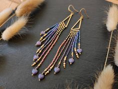 Playful fringe earrings with small love heart beads and fire-polished beads Color: purple and blue with opaque violet love hearts RECURRING - this earring design will return to the shop as long as all materials are available These beaded earrings were made with Miyuki Delica, shimmering Czech beads and brass beads. The design is mirrored -  the longest part of the fringe is on the inner side - towards the neck - and the shortest part on the outer side. The strands are beaded onto a finding in the form of a pointy triangle. The beads were threaded with very fine beading thread which makes the fringe extra flexible and smooth. For the earring's color scheme the lustered Miyuki Delica were matched to the motif and fire-polished beads which decorate the ends of the fringe. 14 different bead ty Purple Beaded Earrings, Elegant Purple Beaded Earrings With Faceted Beads, Purple Fringe Beaded Earrings As Gift, Purple And Gold Beaded Earrings, Purple Fringe Earrings, Handmade Purple Dangle Heart Earrings, Handmade Purple Heart Dangle Earrings, Purple Faceted Beaded Earrings, Jewelry Design Earrings