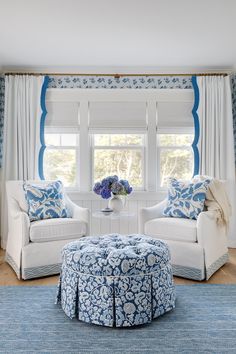 a blue and white living room with two couches, a coffee table, and a round ottoman