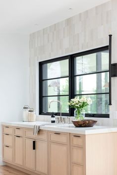 a kitchen with two windows and a sink in front of the window is decorated with white flowers