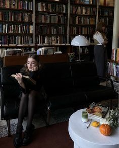 a woman sitting on a couch in front of a bookshelf filled with books