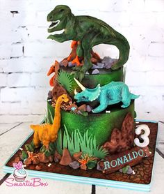 a birthday cake decorated with dinosaurs and rocks