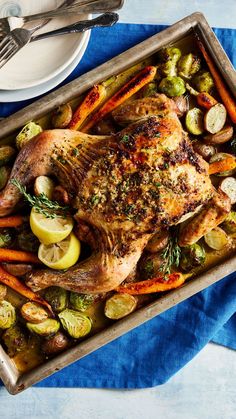 a roasting pan filled with roasted chicken, carrots and brussel sprouts