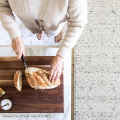 a woman cutting up a piece of bread on top of a wooden cutting board