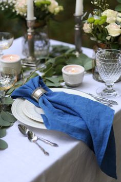 the table is set with candles, plates and napkins