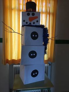 a snowman made out of three boxes sitting on top of a table next to a window