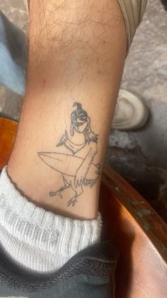 a person with a small tattoo on their ankle that has a girl riding a surfboard