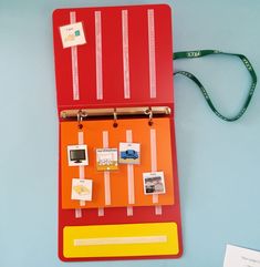 an orange and red clipboard with pictures attached to it on a blue surface next to a lanyard