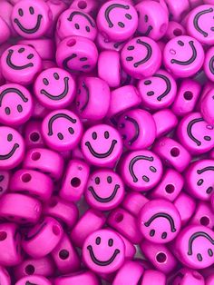 pink beads with black smiley faces are shown in close up view on the surface, as if they were made out of plastic