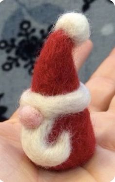 a hand holding a small red and white santa clause ornament