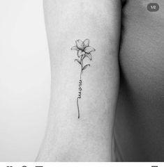 a small flower tattoo on the left arm and shoulder, with words written in cursive