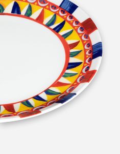 an oval plate with colorful designs on the rim and red trim around the edge, against a white background