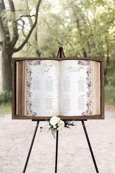 an open book with flowers on it sitting on top of a tripod