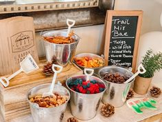 there are many different types of food in buckets on the table with pine cones