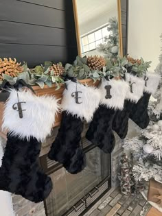 stockings hanging from a mantel decorated with greenery, pine cones and silver bells