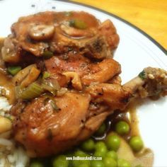 a white plate topped with meat and vegetables covered in sauce on top of green beans