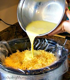 someone pouring cheese into a pot on top of a stove with plastic wrap around it