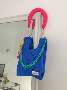 a blue purse hanging from the side of a white door with a pink handle and chain attached to it