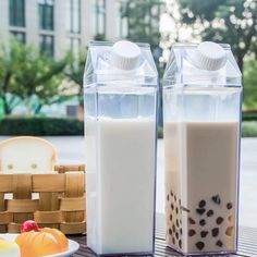 two bottles of milk sitting on top of a wooden table