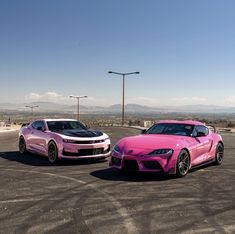 two pink sports cars parked next to each other