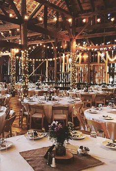 tables and chairs are set up for an event with lights strung from the ceiling above them