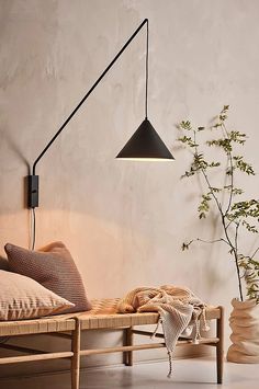 a room with a bed, plant and lamp on the wall