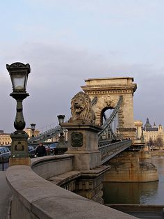 an old bridge with lions on it next to the water and cars parked near by