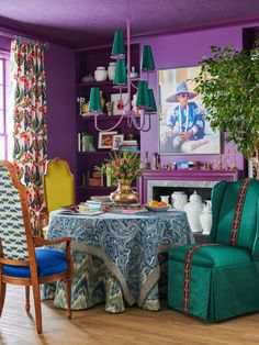 a dining room with purple walls and green chairs, blue table cloth on the table