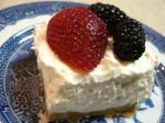 a piece of cake with whipped cream and berries on top sits on a blue plate