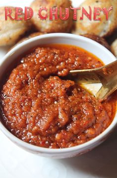 a white bowl filled with red sauce next to some mini muffins on a plate