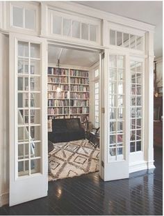 a living room filled with lots of furniture and bookshelves next to a doorway