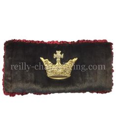 a crown is laying on top of a black and red fur pillow with gold trim