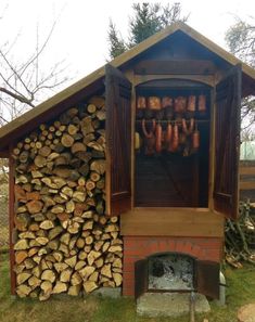 an outdoor bbq with wood stacked on the side and logs piled up behind it