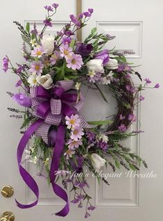 a wreath with purple and white flowers on the front door